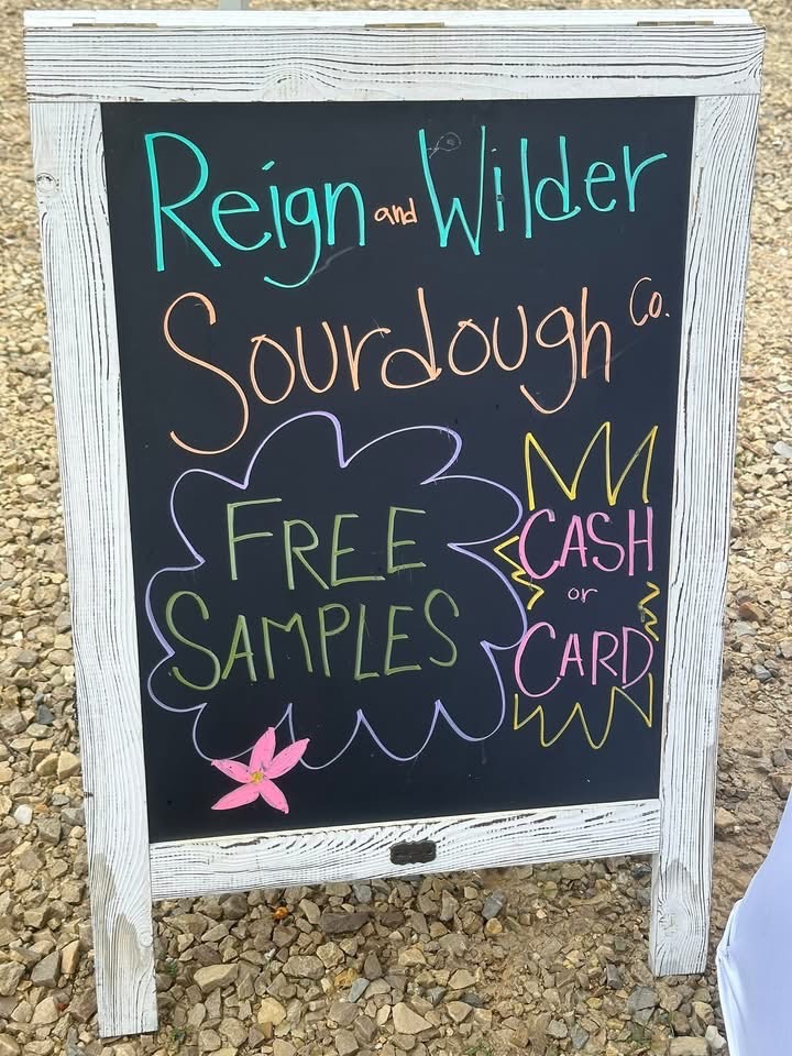 Reign & Wilder booth sign and free samples display at a market